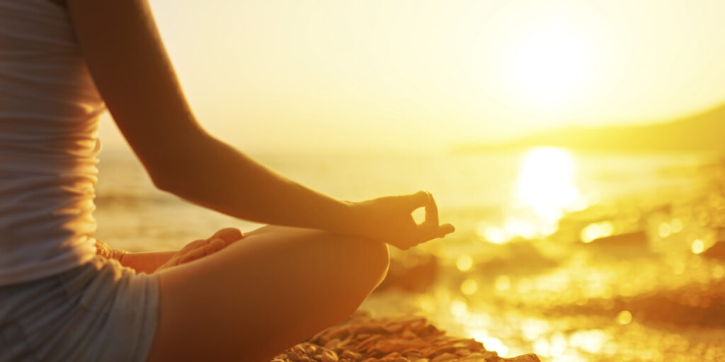 hand of woman meditating in a yoga pose on beach